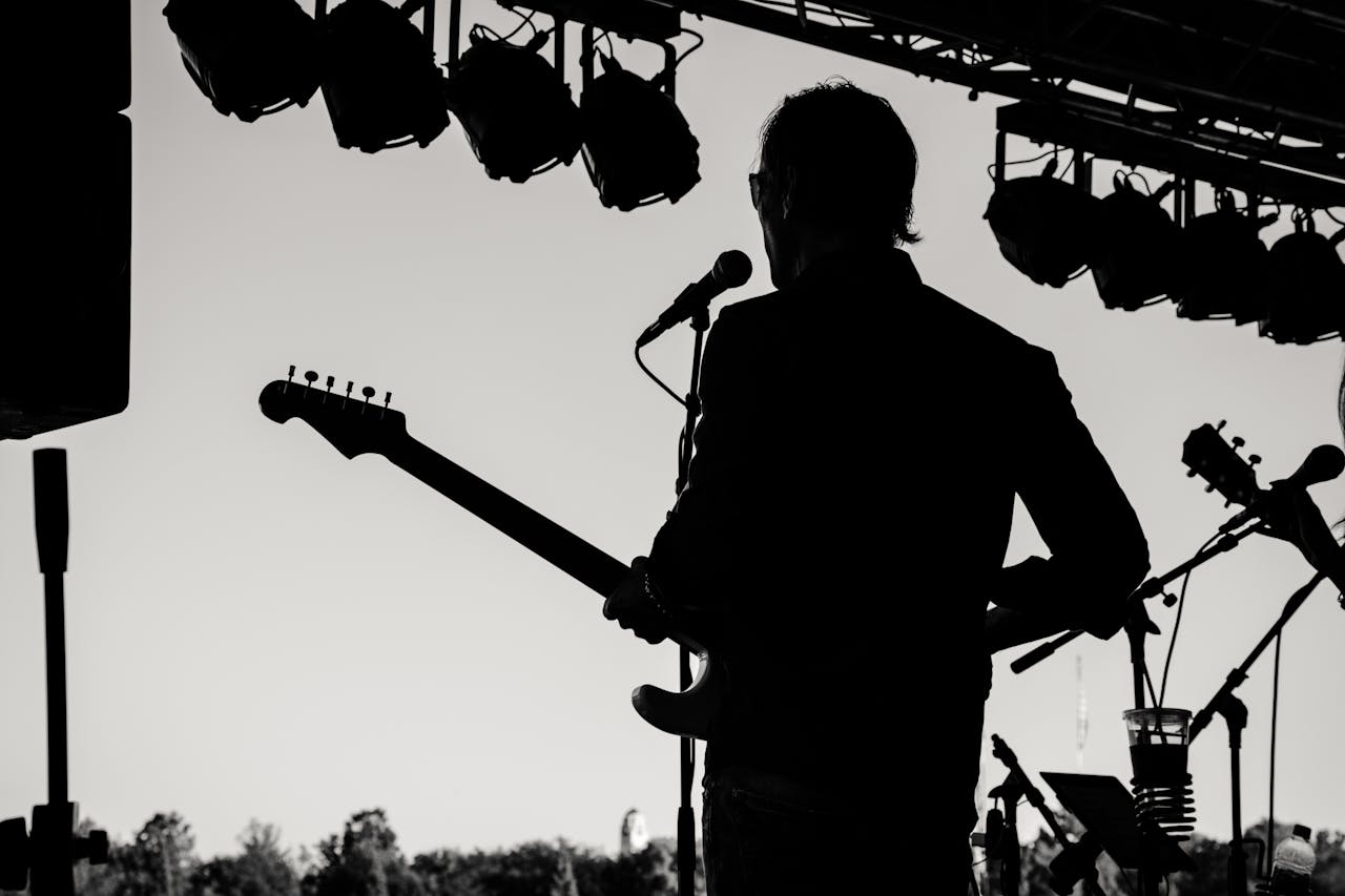 about-01 Silhouette of a guitarist performing at an outdoor concert, capturing musical essence.