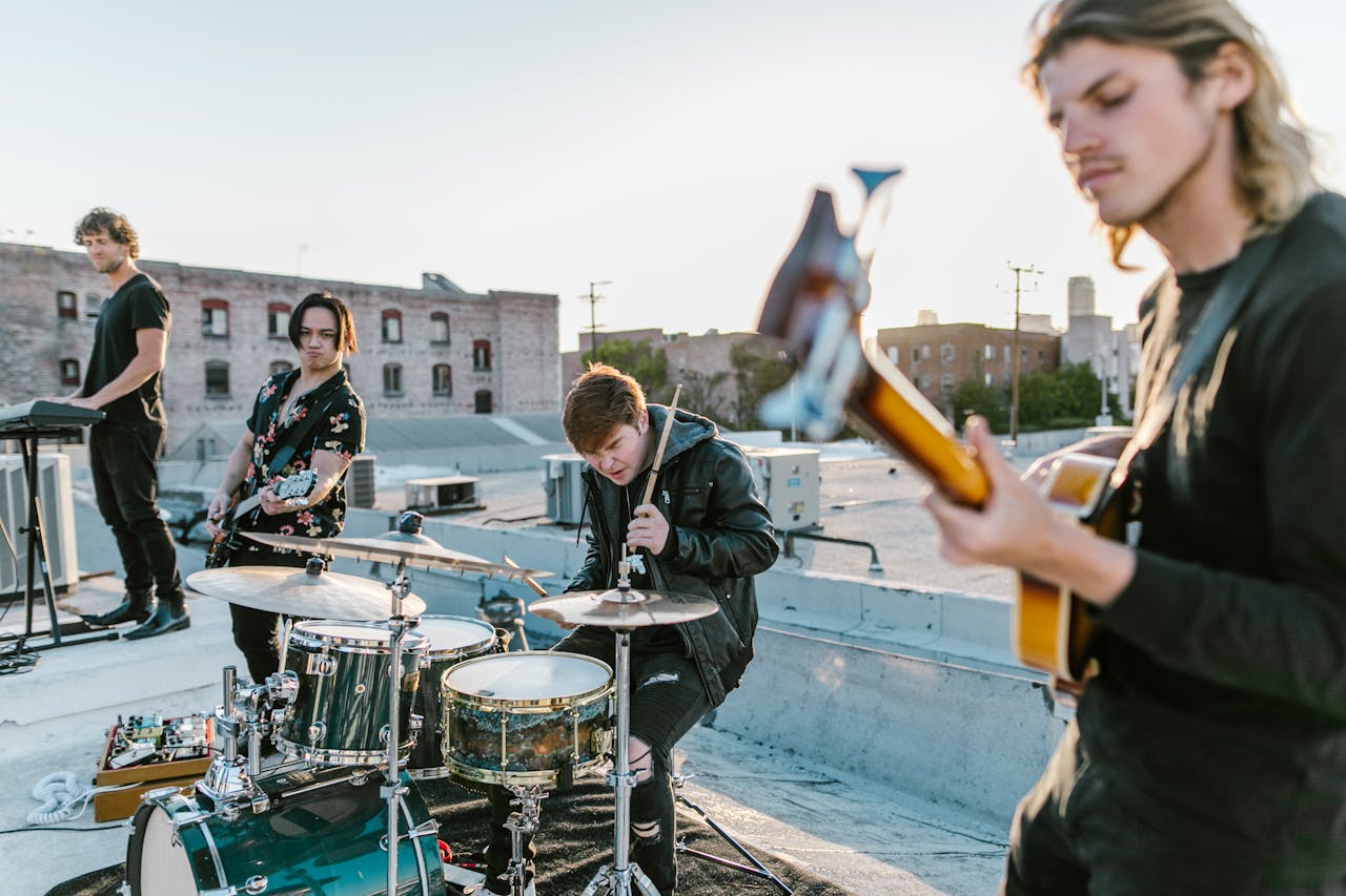 A group of musicians perform on a rooftop with instruments, capturing a lively sunset outdoor performance.