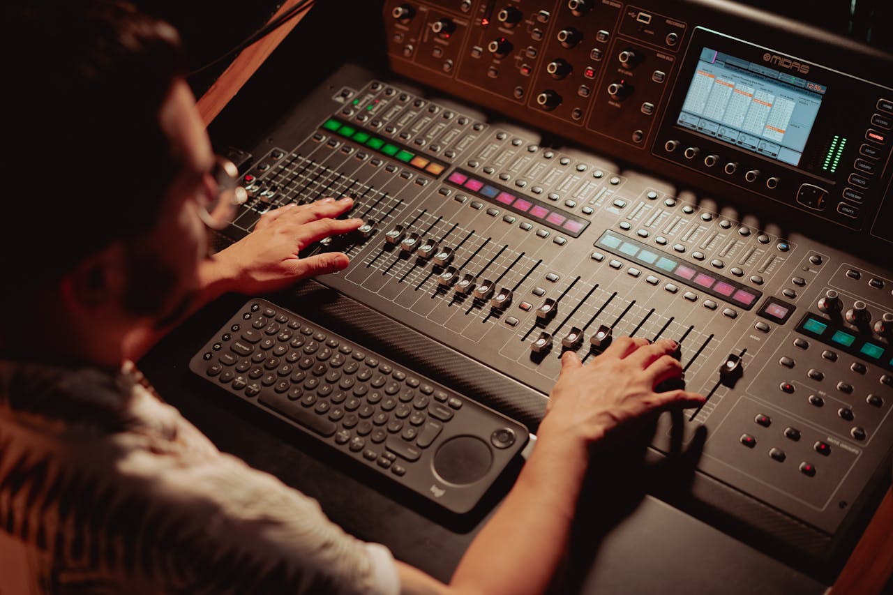 Audio engineer using mixing console in recording studio, adjusting sound levels.