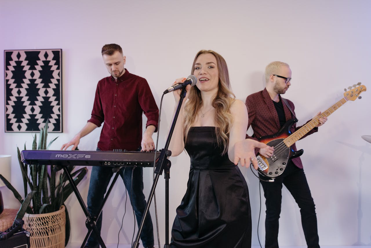 A trio performing with keyboard, electric guitar, and singer indoors.